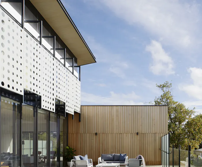 Vertical timber cladding meeting a perforated facade